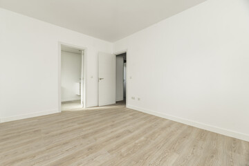 Large empty room with white painted walls, white wooden skirting boards, doors leading to two rooms...