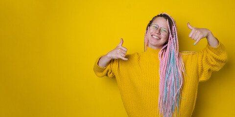 Young woman with afro braids wearing yellow sweatshirt and glasses. Shaka sign concept. Isolated...