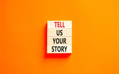 Foto op Plexiglas Tell us your story symbol. Concept word Tell us your story on beautiful wooden block. Beautiful orange table orange background. Business tell us your story concept. Copy space. © Dzmitry