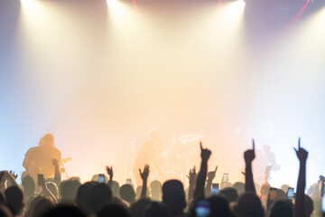 Crowd raising hands under bright light - rock concert