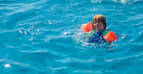 Swimming lessons at the hotel. Child at the resort. Boy in a bathing suit near the pool.