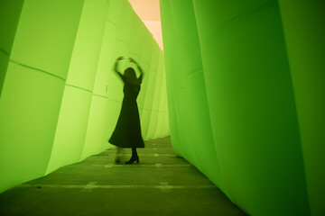 silhouette of a woman in a black dress dancing in a green tunnel 