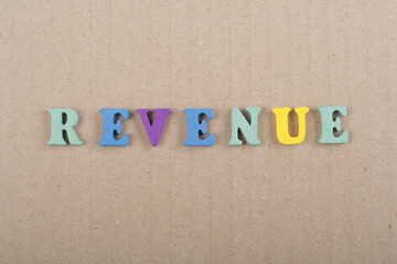 REVENUE word on wooden background composed from colorful abc alphabet block wooden letters, copy space for ad text. Learning english concept.