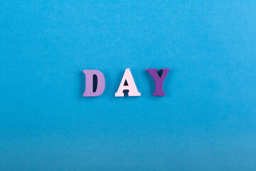 DAY word on blue background composed from colorful abc alphabet block wooden letters, copy space for ad text. Learning english concept.
