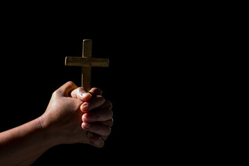 Woman person hand with jesus christ cross praying in dark background. Female christian worship to...