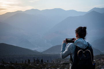 Mujer turista tomando una foto en los cerros de Tilcara, Jujuy, Argentina - obrazy, fototapety, plakaty