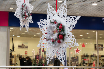 A white, large Christmas toy made of cardboard, in the form of a snowflake. A large, white, paper snowflake, on a ribbon.