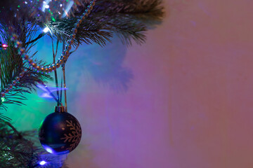A Christmas toy in the form of a ball on the branches of a fir tree. A transparent, bright toy, on the branches of a Christmas Tree.