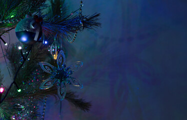 A Christmas toy in the form of snowflakes on the branches of a fir tree. A transparent, bright toy, on the branches of a Christmas Tree.