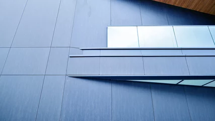 Fotobehang A view at a straight facade of a modern building with a dark grey facade. Dark grey metallic panel facad. Modern architectural details.  © Grand Warszawski