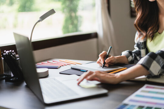 Female artist designer working on laptop to design and drawing logo brand on graphic tablet - Powered by Adobe