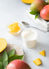 Greek style yogurt with mango and fresh fruits on light board. Top view.