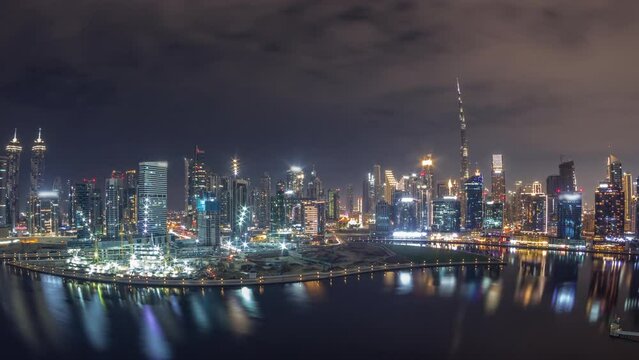 Aerial panorama of Dubai Business Bay and Downtown during all night with the various skyscrapers and towers along waterfront on canal night timelapse. Construction site with cranes covered by fog