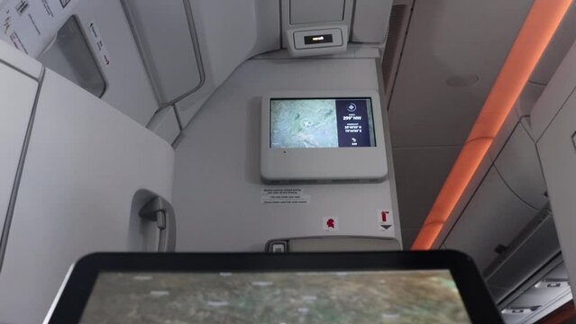 The flying plane on the passenger monitor with a change view on the monitor on a wall