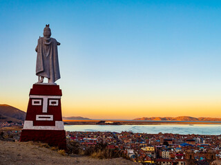 Stunning aerial view of lake Titicaca at sunset from Huajsapata Hill viewpoint with the monument to Manco Capac in foreground, Puno, Peru