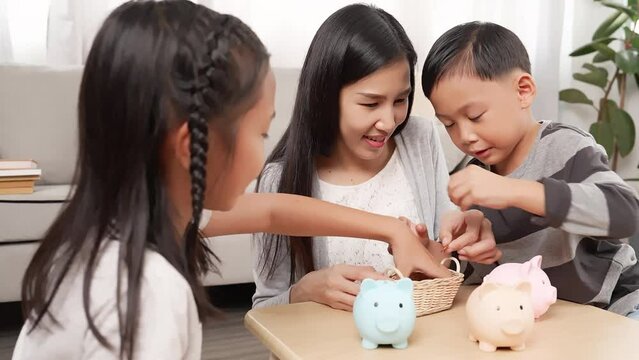 Asian Single mom preschool son little daughter dropping coins into piggy bank for saving Happy family saving money for new housing dream future education children Teach kids be thrifty concept
