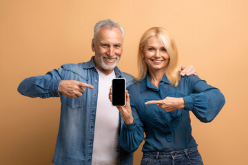 Happy senior couple showing smartphone with black screen