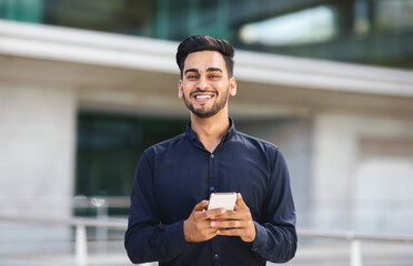 Young Arabic businessman with cellphone engrossed in texting outside