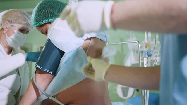 Male doctor injecting Epidural Anesthesia for pregnancy Labor during childbirth for woman pathient in hospital. Spinal anesthesia. Doctor makes a puncture in the lumbar spine.