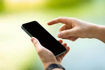 Hands of millennial caucasian man in casual typing on phone empty screen in city, enjoy chat