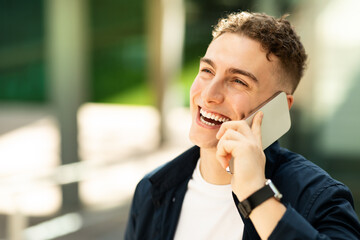 Cheerful glad attractive millennial caucasian man enjoy lifestyle, calling by phone, got good news in city