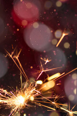 Burning sparkler with red bokeh light background. New year party background. New year sparkles.