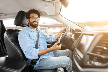 Happy millennial indian guy driver in casual outfit and eyeglasses