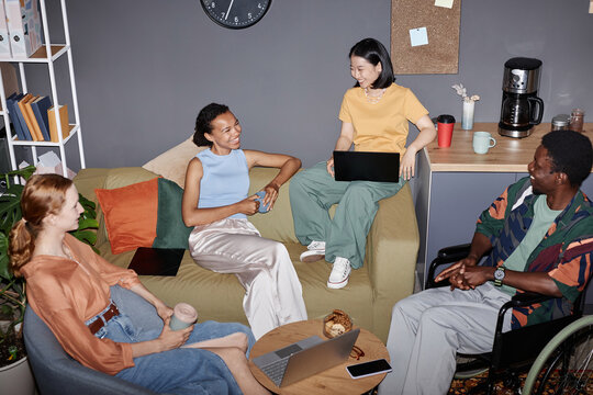 Multiethnic group of young professionals meeting in office lounge with flash
