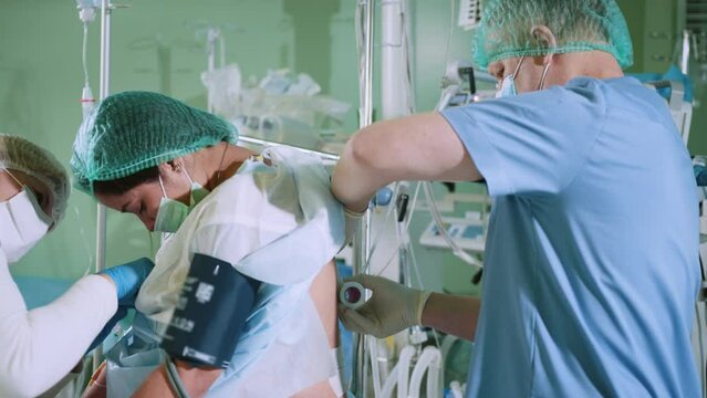Doctor inserts a needle into the patient's spine for anesthesia. Pain relief in preparation for surgery. Spinal anesthesia injection, epidural anesthesia or nerve block. Anesthesiologist at work