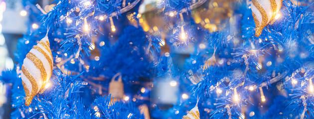 Banner Blurred Background Blue Christmas tree decorated gold bauble ornament in holiday winter xmas bokeh light. Panorama backdrop Gold light Blue christmas tree in cozy living room with copy space