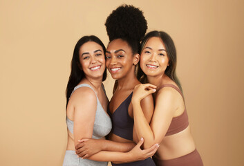 Three diverse women smiling, embracing their natural beauty in underwear