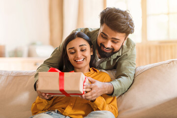 Joyful couple sharing a gift moment at home