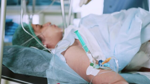 An anesthesiologist injects intravenous anesthesia with a large syringe into the patient's arm on the operating table. Surgery with general anesthesia. Anesthesiologists administer general anesthesia