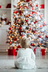 cute child with christmas tree. happy baby sitting near a fir tree