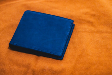 Blue handmade leather wallet on a brown velvet background. Top view.