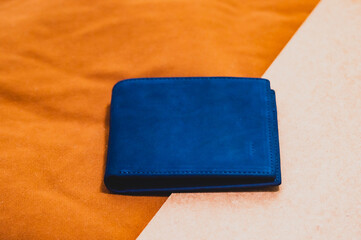 Blue handmade leather wallet on a brown velvet background. Wooden background. Top view.