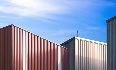 Group of aluminium industrial warehouse buildings in factory area against blue sky background, low...