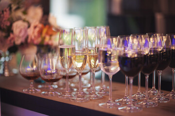 Glasses of red wine, champagne in a row on a buffet table. Table with alcohol poured into glasses. Catering services background with glasses of wine on bartender counter in restaurant.