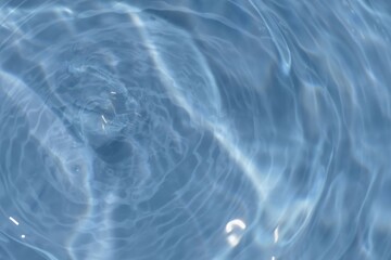 Defocus blurred transparent blue colored clear calm water surface texture with splashes reflection. Trendy abstract nature background. Water waves in sunlight with copy space. Blue watercolor shine.