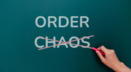 Hand writing chaos and order on blackboard