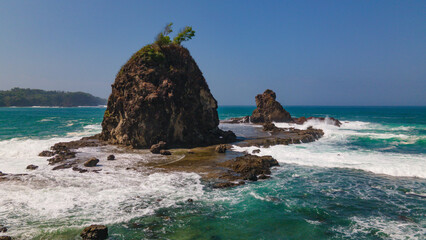 Rocky shoreline of Watu Lumbung Beach, Indonesia. Tidal waves hits the coral rock