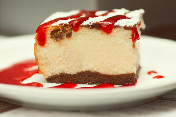 Tasty morning concept. Slice of cheese cake with sugar powder and strawberry jam in cafe. Daylight. Close up. Outdoor shot