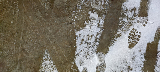 Melted snow on the road in winter. Snow slush on the road surface and sidewalk. Bicycle tire and shoe tracks in the snow.