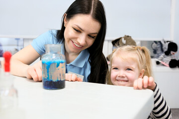 Little scientist. Curious daughter play with mom engaged at education activity make funny experiment. Interested small girl watch elder sister doing chemical test use chemistry set kids