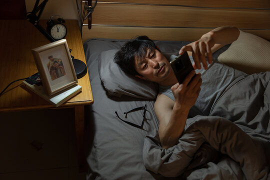 A middle-aged man lying in bed using a mobile phone