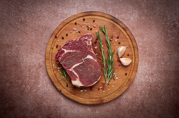fresh raw rib eye steak, on a cutting board, top view,