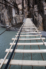 Suspension Hussaini bridge in Passu, Upper Hunza. Dangerous scary bridge, Karakoram mountains and Hunza river. 