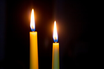 Two candles on a dark background, copy of space
