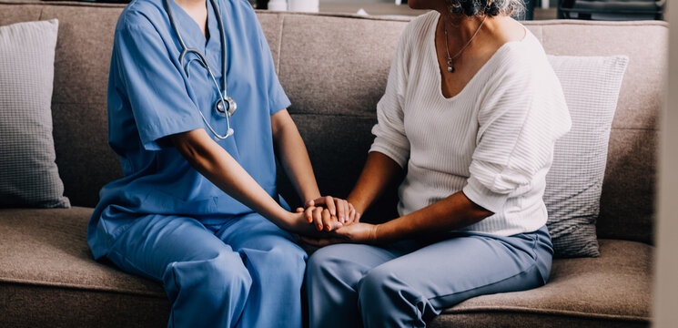 Happy senior woman visiting doctor, getting optimistic news after medical checkup, therapy. Therapist holding hand of old patient, giving hope, support, congratulating on goor treatment result