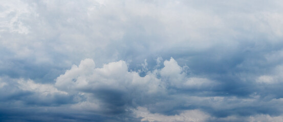 White curly clouds on a gloomy gray-blue sky